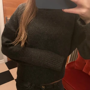 Mörkgrå stickad polotröja Zara - Säljer en mörkgrå stickad polotröja med lång ärm och ribbade muddar. Tröjan har en hög krage som ger en chill vibe och är perfekt för kyliga dagar. Passformen är normal och materialet känns mjukt och skönt mot huden. 