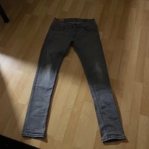 Grå jeansbyxor i slim fit - Säljer ett par grå jeansbyxor med smal passform och klassisk femficksdesign. Jeansen har en snygg tvättad look och raka ben. Perfekta för dig som gillar en stilren och enkel stil.