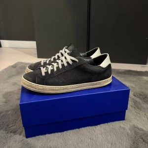Mörkblå mockaskor från P448 - Snygga svarta sneakers från P448 med grå snörning och vit häl. Skorna är tillverkade i mocka med perforerade detaljer på sidorna och har en platt sula i beige. Allt og medföljer. Nypris ca 2800!