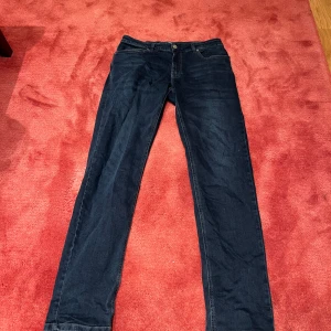 Mörkblå jeans från Hansen & Jacob - Storlek: 32 midja 34 längd.                            Snygga mörkblå jeans från Hansen & Jacob med klassisk femficksdesign och raka ben. Jeansen har en stilren look med diskreta sömmar och är tillverkade i mjukt denimtyg som sitter skönt hela dagen.