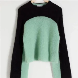 Mintgrön och svart stickad tröja - Superfin stickad tröja i mintgrönt och svart med lite croppad passform. Tröjan har lång ärm och är stickad, vilket ger en mysig och trendig look. Perfekt till jeans för en chill stil!🥰