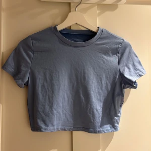 Ljusblå croppad topp från SHEIN - En enkel och stilren ljusblå croppad topp från SHEIN. Toppen har rund halsringning och korta ärmar, tillverkad i mjuk polyester med lite stretch för skön passform. Perfekt att matcha med jeans eller kjol för en chill look.