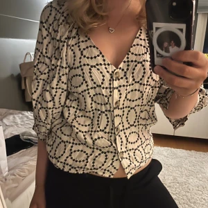 Mönstrad blus - Säljer en såå fin beige blus med svarta prickar i ett coolt mönster. Blusen har v-ringning, trekvartsärmar och knappar framtill.😽