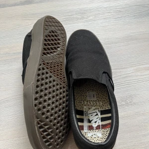 Svarta Vans slip-on sneakers - Vans BMX x Dennis Enarson Slip-On “Black” sneakers – herrskor storlek 42. Skick: Helt nya – aldrig använda. Originalkartong saknas.