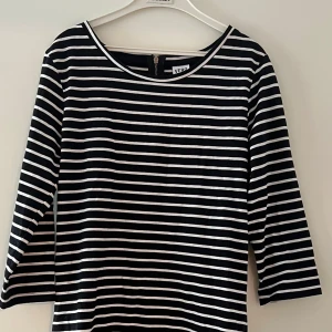 Randig kortklänning från Vero Moda - Snygg svartvit randig klänning från Vero Moda i storlek S. Modellen har trekvartsärm, rund hals och dragkedja i ryggen. Mjuk och skön som sitter normalt på kroppen. Perfekt för dig som gillar enkel och stilren design.