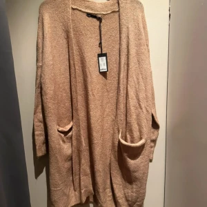 Beige kofta från 157 med fickor - Mysig beige kofta från 157  stora fickor framtill. Koftan är stickad och har långa ärmar, 