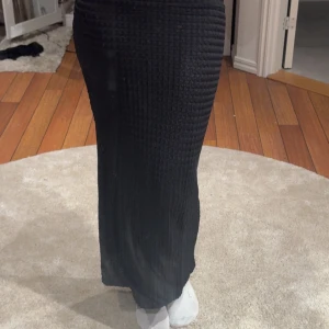 Svart ribbad långkjol - Säljer en svart långkjol med ribbad struktur. Kjolen har en tight passform och är gjord i ett stickat. Ifrån lager 157