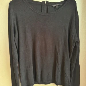 Svart långärmad tröja i viskos  - En svart, enkel och stilren långärmad tröja från Basic U. Tröjan har rund halsringning och en liten dragkedja bak i nacken. Mjuk och tunn i viskos, passar till det mesta. Generös storlek.