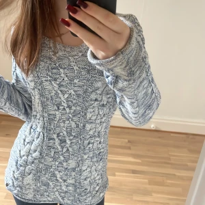 Blåvit stickad tröja från L.O.G.G. - Säljer en blåvit stickad tröja från L.O.G.G. i storlek S. Tröjan har ett snyggt flätmönster framtill och är långärmad med rund hals. Perfekt för dig som gillar mysiga och stilrena plagg med lite chunky känsla. Passar dig som vill ha en normal passform.