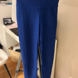 Blå leggings med struktur från Amisu XS - Säljer ett par blå leggings från Amisu i storlek XS. De har en cool 3D-struktur och scrunch-detalj bak som framhäver formen. Materialet är stretchigt och passar perfekt för dig som gillar att sticka ut med din outfit.
