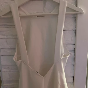 Vit långklänning från Zara XS - Säljer en stilren vit långklänning från Zara i storlek XS. Klänningen har en tight passform, är ärmlös och har breda axelband med snyggt skuren rygg. Materialet känns mjukt och har en lätt stretch. Perfekt för dig som gillar minimalistisk och clean stil.