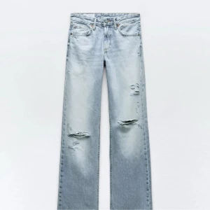 Ljusblå slitna raka jeans Zara - Säljer ett par ljusblå jeans med raka ben och slitna detaljer på låren och knäna. Jeansen har klassisk femficksdesign och är tillverkade i denim. Perfekta för en avslappnad och trendig look.