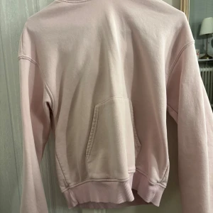 Ljusrosa hoodie från Gina Tricot - Ljusrosa hoodie från Gina Tricot, Basically Basics-kollektionen. Tröjan har huva, magficka och ribbade muddar vid ärmslut och nederkant. Mjuk och skön i bomullsmix, perfekt för chill dagar. Enkel och clean design utan mönster eller tryck.