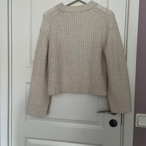 Beige stickad tröja från Gina Tricot - Supermysig beige stickad tröja från Gina Tricot i storlek XXS. Tröjan har grovstickat mönster, ribbade muddar och en rund halsringning. Perfekt för lager på lager under kyliga dagar.