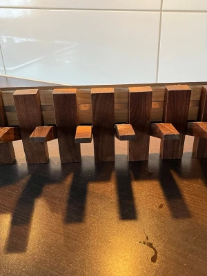 Vägghängd kroklist i valnötsträ - Säljer en unik och stilren kroklist i mörkt trä med 8 utfällbara krokar. Perfekt för att hänga upp jackor, väskor eller accessoarer. Listen har en modern design med rektangulära former och kan enkelt monteras på väggen. Passar bra i hallen eller sovrummet. Helt ny! Kostade 875 kr 