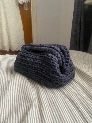 Mörkblå handvirkad tygväska - Unik handvirkad väska i mörkblått tyg med rektangulär form och integrerade handtag. Perfekt för dig som gillar personliga accessoarer. Väskan är mjuk och har en cool, chunky look tack vare det grova garnet.