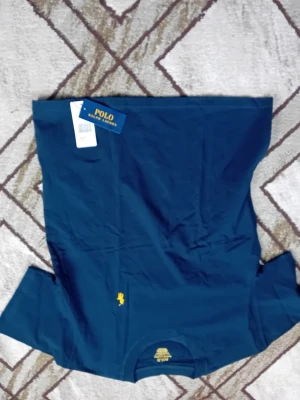 Marinblå t-shirt från Polo Ralph Lauren - Snygg marinblå t-shirt från Polo Ralph Lauren med klassisk gul logga broderad på bröstet. T-shirten har rund hals och korta ärmar. Tillverkad i mjuk bomull som känns skön mot huden. Perfekt för en clean och stilren look.