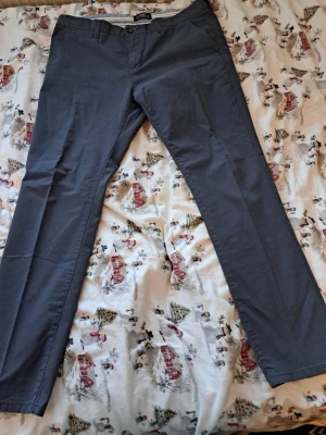 Fina ljusiga byxor i nyskick – storlek 36/32 – Stretch - Säljes: Ett par snygga byxor från Kappahl i mycket fint skick. Endast använda 2 gånger – helt nyskick och väldig fina. Detaljer: * Storlek: **36/32** * Material: **98 % bomull, 2 % elastan** * Färg: mörkblå (se bilder) * Skick: **Nyskick** Ett par stilrena byxor i en mörkare nyans. Byxorna har en klassisk passform och kan enkelt matchas med olika överdelar för en mångsidig look. Bekväma byxor med lite stretch som passar både till vardag och jobb.  Vid övriga frågor skicka gärna meddelande. 