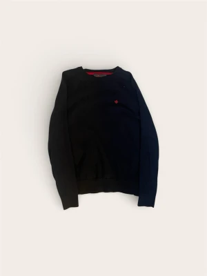 Svart tröja från Morris - Klassisk svart tröja från Morris med rund halsringning och diskret röd logga broderad på bröstet. Tröjan har långa ärmar och ribbade muddar. Perfekt för dig som gillar stilrena plagg med en liten detalj. S men passar bättre xs