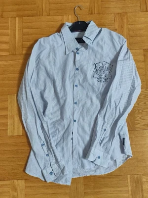 Vitt Armani Skjorta - Elegant randig Armani Jeans skjorta för män. Bra skick inga skador/slitage, Storlek L. Stillig Tryck på bröstet som ger en extra touch av exklusivitet.  Hör av vid frågor/funderingar. PRIS KAN DISKUTERAS!