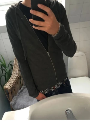 Stickad tröja - Stickad zip hoddie från Jack and Jones, Säljer en stilren mörkgrå hoodie med dragkedja och huva. Hoodien har en enkel design utan tryck, långa ärmar och dragsko i huvan. Perfekt att slänga på sig över en t-shirt för en avslappnad look.