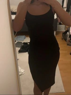 Svart tight klänning med slits  - Ribbad svart klänning med liten slits på sidan. Spegeln är lite smutsig inte klänningen! :)