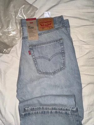 Levi's 569 Loose Straight ljusblå jeans - Ljusblå jeans från Levi's modell 569 Loose Straight med klassisk femficksdesign och rakt ben. Jeansen har Levi's ikoniska läderpatch bak i midjan och röd logotagg på bakfickan. Tillverkade i bomullsdenim för en avslappnad look.