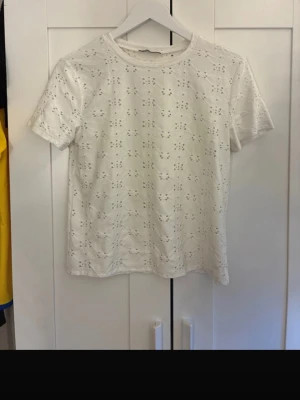 Vit kortärmad blus med broderi - Söt vit blus med korta ärmar och broderade hålmönster över hela tyget. Rak passform och rund halsringning, perfekt till jeans eller kjol. Lätt och luftig känsla, passar bra till vår och sommar. Tröjan finns även på min vinted (selmaoverfjord)