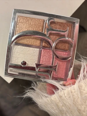 Dior Palette - Dior Palette med fyra skimrande nyanser: champagne, brons, pärlvit och rosa. Paletten har en lyxig silverfärgad förpackning med stor Dior-logga och passar perfekt för att skapa glow och highlight på kindbenen. Pressat puder med silkeslen finish.