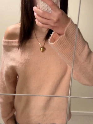 Ljusrosa stickad tröja med bred hals - Supermjuk ljusrosa stickad tröja med bred, ribbad halsringning som kan bäras off-shoulder. Tröjan har långa ärmar och ribbade muddar vid ärmslut och nederkant. Perfekt för lager-på-lager och chill stil. Materialet känns fluffigt och mysigt.