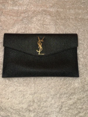 Clutch från YSL - Svart uptown pouch från ysl! Använd fåtal gånger så i väldigt fint skick. Inhandlades 2024 på NK stockholm. Kartong, dustbag och kvitto finns. Priset på väskan har ökat sen inköpet. Nypris just nu 7000kr. Denna annons ligger ute på flera sidor! Pris kan absolut diskuteras ❤️