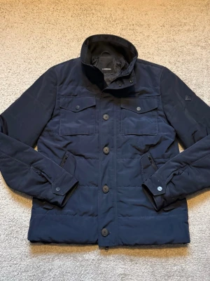 J.Lindeberg jacka - En stilren och mycket snygg J.Lindeberg-jacka, perfekt till våren. En modern design som funkar lika bra till vardags som mer uppklätt.  Jackan är i mycket bra skick och har en diskret och snygg logga på armen som ger en exklusiv känsla.  ✅ Märke: J.Lindeberg ✅ Storlek: M ✅ Färg: Mörkblå ✅ Skick: Mycket bra ✅ Detaljer: Snygg logga på armen ✅ Säsong: Perfekt till våren  En riktigt fin vårjacka med mycket kvar att ge!