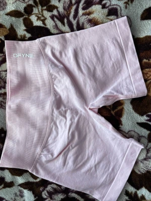 Ljusrosa seamless  DFYNE - Säljer ett par ljusrosa seamless cykelshorts från DFYNE. De har hög midja och är tillverkade i ett stretchigt, mjukt material som passar perfekt för träning eller gym. Loggan sitter diskret framtill i vitt.