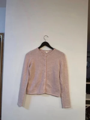 Ljusrosa kofta med rund hals - Söt ljusrosa kofta med rund halsringning och knappar framtill. Koftan har långa ärmar och är tillverkad i ett mjukt, stickat material. Enkel och stilren design som passar perfekt till många olika outfits. 