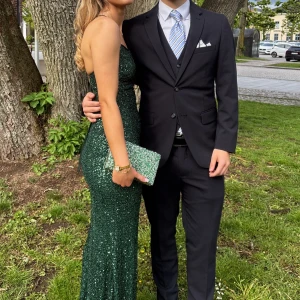 Grön glittrig långklänning - Säljer en elegant grön långklänning med glittriga paljetter. Klänningen är figurnära och axelbandslös, perfekt för speciella tillfällen. Materialet är troligtvis polyester och den har en klassisk, tidlös siluett. Har ej kvar prislapp 