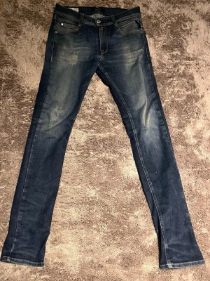 Mörkblå slim fit jeans - Snygga mörkblå slim fit jeans med lätt slitning och klassiska fem fickor. Jeansen har en smal passform och subtila detaljer på bakfickan. Perfekta för en trendig och avslappnad look.