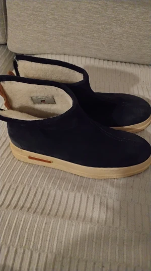 Mörkblåa fodrade boots från Gant st.40 - Säljer ett par mörkblåa boots från Gant med mjukt vitt foder och beige sula. Skorna har mockaliknande material på utsidan och en låg, stilren siluett. Perfekta för kalla dagar när du vill hålla stilen och värmen.