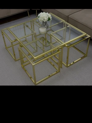 Soffbord i glas och guldmetall - Stilrent soffbord med fyrkantig design, tillverkat i glas och metall med guldfärgad ram. Bordet består av flera mindre bord som kan skjutas in under varandra för flexibel användning. Perfekt som mittpunkt i vardagsrummet för en modern och lyxig känsla.