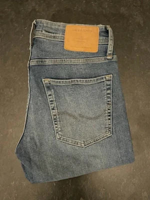 Jack&Jones jeans  - Säljer ett par blåa jack&jones jeans med snygg tvätt, storlek W28/L30, slim fit. Mycket bekväma jeans och är lite stretchiga. Mycket bra skick där de använts fåtal gånger.                                          Nypris 600kr.                                                           Mått: A=38cm B=78cm C=101cm D=17cm.                                Fråga gärna om fler bilder eller om det är något ni generellt undrar!                                       Checka in profilen för liknande jeans!