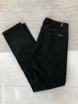 Svarta jeans från 7 For All Mankind - Säljer ett par Superfina oanvända jeans från 7 For All Mankind med otroligt snygg passform. Storlek 29 straight low Waits med stretch. Midja 39 cm, beninnerlängd 82 cm. Matt svart.