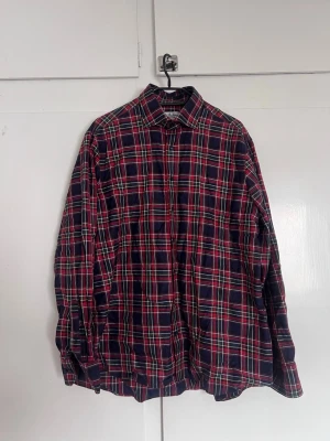 Rutig skjorta i bomull marinröd - Klassisk långärmad skjorta med rött, blått och vitt rutmönster. Skjortan har knappar framtill och är tillverkad i mjuk bomull. Perfekt för en avslappnad och stilren look.