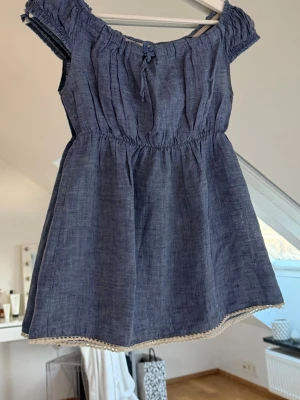 Blå blus med spetskant - Söt blå blus i bomull med offshoulder-modell och resår i midjan. Väldigt mjuk och skön. Knytning framtill och spetskant längst nertill. 