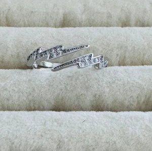 Silverfärgad blixtformad ring - Cool ring i silverfärg med blixtformad design och små gnistrande stenar längs hela ovansidan. Perfekt för dig som gillar unika och trendiga smycken med lite edge. Ringen har en öppen form och är riktigt snygg som statement-piece.