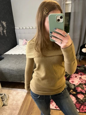 Beige off shoulder stickad tröja - Snygg beige stickad tröja med off shoulder-design och bred ribbad kant upptill. Tröjan har långa ärmar och ribbade muddar vid ärmslut och nederkant. Storlek S