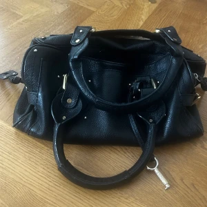 Svart Chloé Paddington  - Saljer min älskade Chloé Paddington väska som är i bra skick. Den har några skador på insidan av väskan och tyvärr saknar den låset. Saknar även två nitar under väskan.  Skriv om du har frågor och priset är förhandlingsbart! Mått: Längd 33 cm Höjd ca 18 cm Djup ca 15 cm. OBS! Jag har inget äkthetsbevis och väskar saknar serienummer därför kan jag inte helt säkert säga att den är äkta. Därför är priset förhandlingsbart