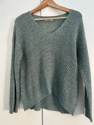 Ljusgrön stickad tröja  - Mysig ljusgrön stickad tröja från JDY med v-ringning och lång ärm. Tröjan har en lätt loose passform och ribbade muddar vid ärmslut och nederkant. Perfekt för lager-på-lager under kyliga dagar. Aldrig använd 