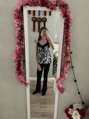 Grön och vit linnetopp med spets - Säljer en snygg linnetopp från Amisu i storlek XS. Toppen är grön och vit med ett abstrakt mönster och har tunna axelband. Ovanför bysten finns dekorativ grön spets och tyget har en glansig satinliknande känsla. Perfekt för dig som vill sticka ut lite extra.