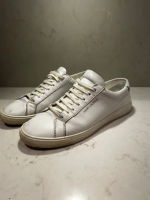 Vita Saint Laurent  - Hola👋Säljer dessa sjukt sjukt snygga Saint Laurent sneakers, perfekta till sommaren för finare stunder och i vardagen• Pris 2100kr• Skick 7/10 färgen lossnat lite och en slags ”skrap sår”  men fortfarande sjukt snygga på och inget man direkt tänker på när man har de på, och pytte lite slitna under skon• Storlek 42, 27,5cm• Bättre pris vid snabb affär•kom för fler bilder osv i pm• Caio 👋