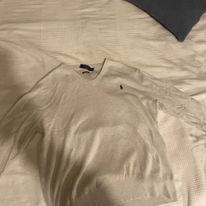 Ralph Lauren tröja  - Säljer en snygg V-ringad Ralph lauren tröja i går färg. Perfekt med skjorta eller piké under för festliga tillfällen. Mycket bra skick, ända defekten är att lappen åkt av lite på ena sidan men inget så märks vid användning såklart. Priset är diskuterbart vid snabb affär. 