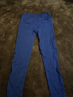 Blå leggings i stretch, storlek XS - Säljer ett par blå leggings i storlek XS. De är tillverkade i ett stretchigt material med 92% polyamid och 8% elastan, vilket gör dem riktigt bekväma och följsamma. Perfekta för dig som gillar en tight passform och vill ha något enkelt och stilrent.